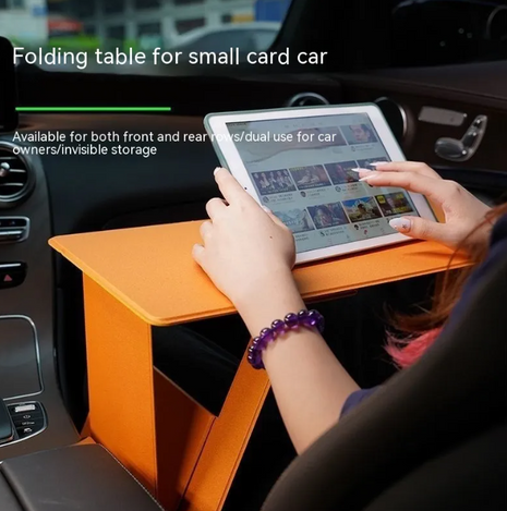 Orange folding table in a car with a person using a tablet, text indicating it's for small cars.