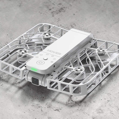 White drone with remote control on a gray surface